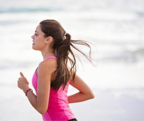 Mujer corriendo al lado de la playa