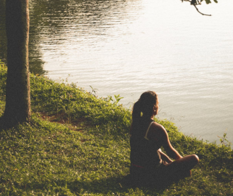 Mujer meditando a orillas de un rio